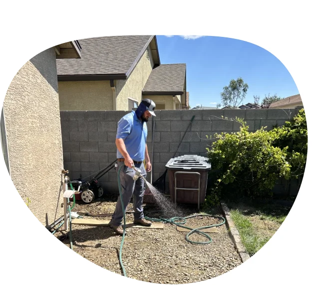 A man is using a hose to clean the yard.