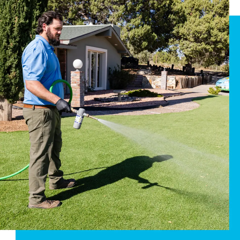 A man spraying water from the hose of his lawn.