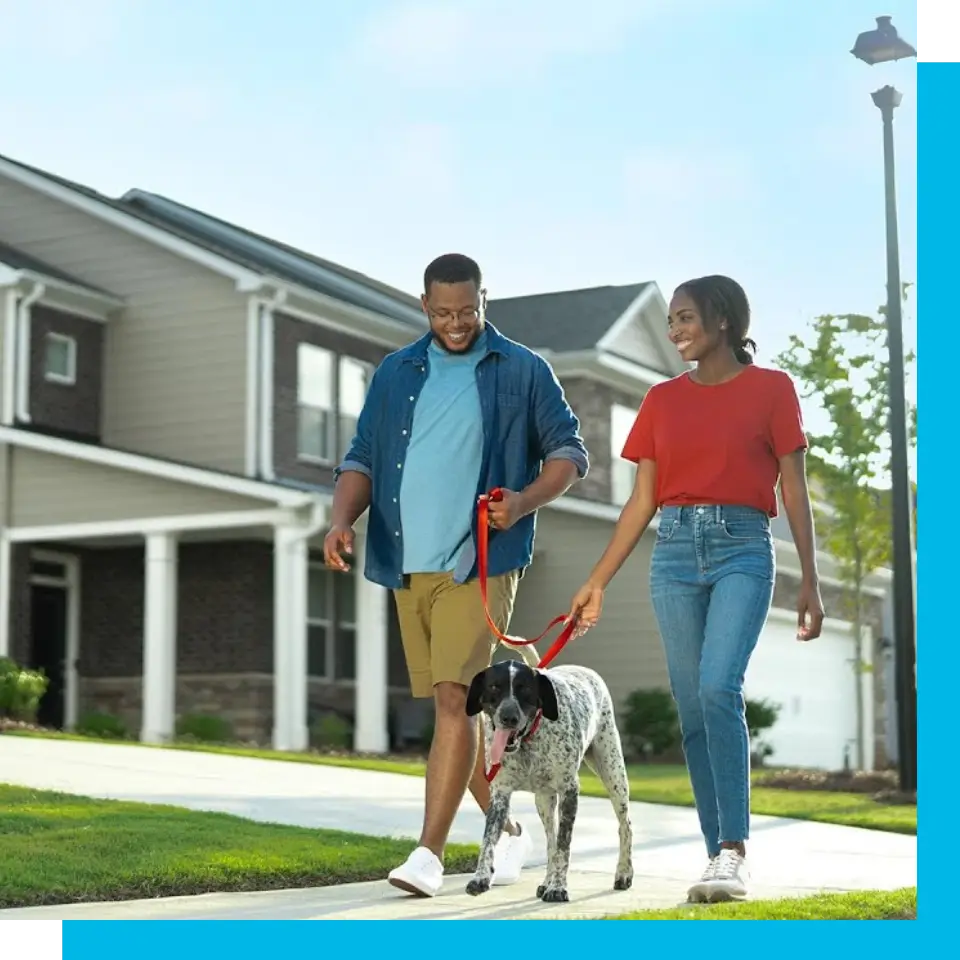 A man and woman walking their dog down the street.