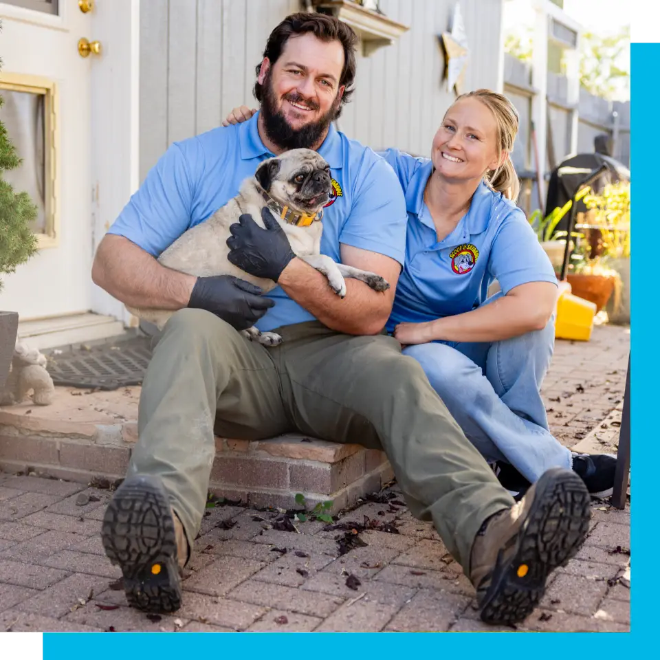 A man and woman holding a dog on the ground.